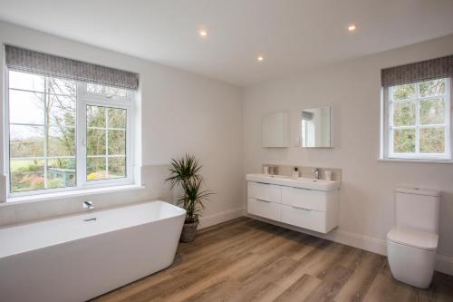a white bathroom with a tub and a sink at Peaceful Woodland Retreat near Clifton, Bristol in Bristol