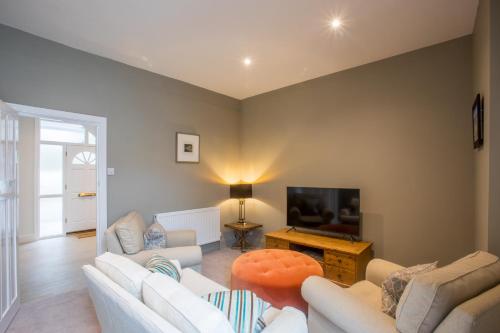 a living room with white furniture and a flat screen tv at Peaceful Woodland Retreat near Clifton, Bristol in Bristol