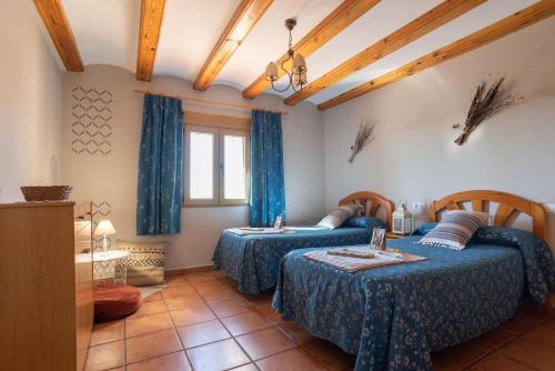 duas camas num quarto com lençóis azuis e cortinas azuis em Torre Amador em Culla