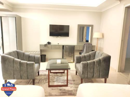 a living room with two chairs and a tv at Grand Plaza Sheikh Zayed in Kafr Abū ʼumaydah