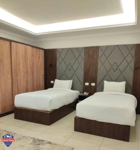 two beds in a hotel room with white sheets at Grand Plaza Sheikh Zayed in Kafr Abū ʼumaydah