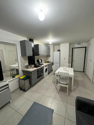 uma grande cozinha com uma mesa e uma mesa e cadeiras em Cosy Appartement em Le Blanc-Mesnil