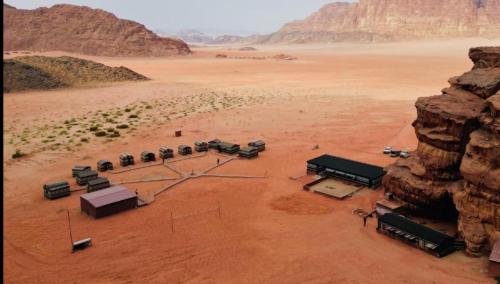 eine Luftansicht einer Wüste mit einer Fahrzeuggruppe in der Unterkunft Magic Bedouin Night in Wadi Rum