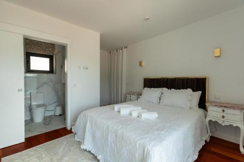 a bedroom with a large white bed with towels on it at Quinta Flor de Lis, Gerês in Vieira do Minho
