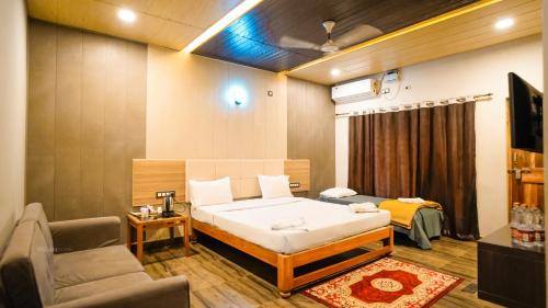 een slaapkamer met een bed, een bank en een tv bij Ansh Resort, Dandeli in Dandeli