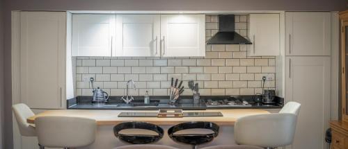 a kitchen with white cabinets and a table with chairs at Abbey Holidays Loch Ness Luxury Self Catering 2 Bedroom Cottages in Fort Augustus