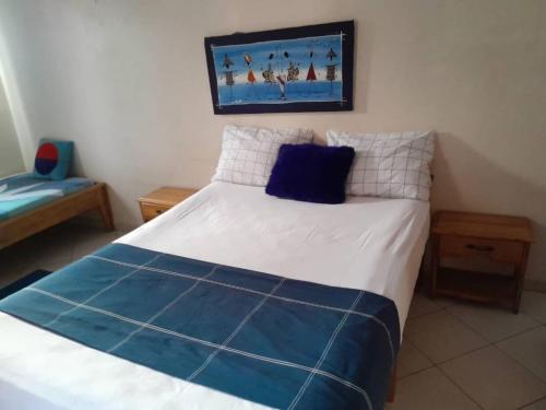 1 dormitorio con 1 cama con almohadas azules y blancas en Résidence Keur Fleurie Sénégal, en Rufisque