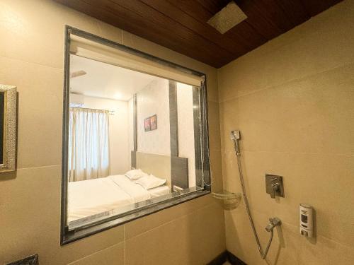 a bathroom with a window with a bed and a shower at Zestin Hill Resort Lonavala in Lonavala