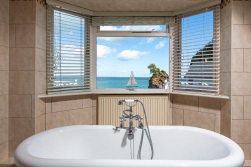 a bath tub in a bathroom with a view of the ocean at Cary Arms & Spa in Torquay