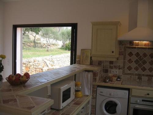 eine Küche mit einer Theke mit einer Mikrowelle und einem Fenster in der Unterkunft Charmante Petite Maison & Spa à Bulles & Grande Terrasse Plein SUD ! in Entrecasteaux