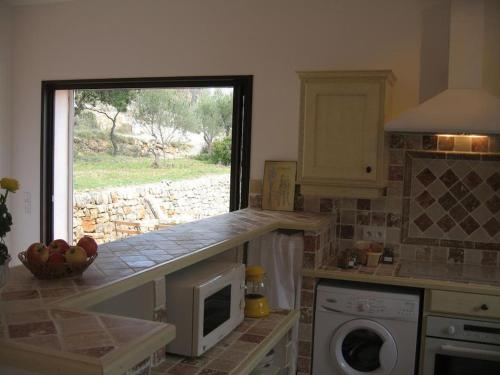 a kitchen with a counter with a microwave and a window at Charmante Petite Maison & Terrasse Plein SUD au Calme ! in Entrecasteaux