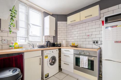 a kitchen with white cabinets and a washer and dryer at NEW - Serviced Apartment - Exel & O2 & Canning Town - home away from home in London