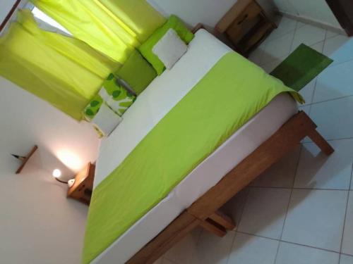 a bed with green and white sheets on it at Résidence Keur Fleurie Sénégal in Rufisque