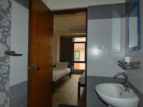 a bathroom with a sink and a bedroom with a bed at Paradise Guest House in Kathmandu
