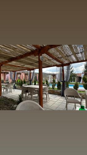 a patio with tables and chairs under a wooden canopy at Brvnara Ruza Rumena in Mionica