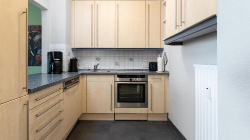 a small kitchen with wooden cabinets and a sink at HomeSweetHome Wedel in Wedel