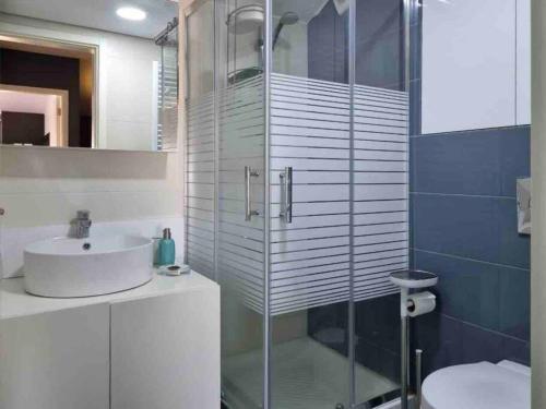 a bathroom with a glass shower and a sink at Modern 2BR Duplex in Afqā