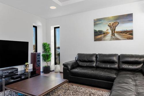 a living room with a leather couch and a flat screen tv at Flott moderne hus langs elven! in Fredrikstad