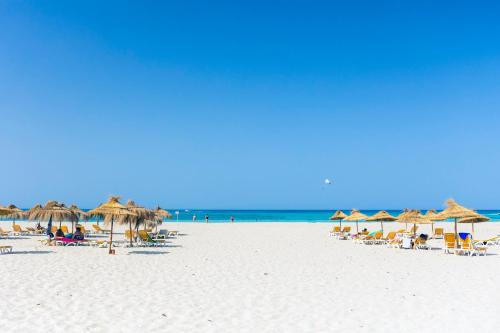 een strand met parasols en stoelen en de oceaan bij TMK Marine Beach - All Inclusive Seafront resort in Triffa