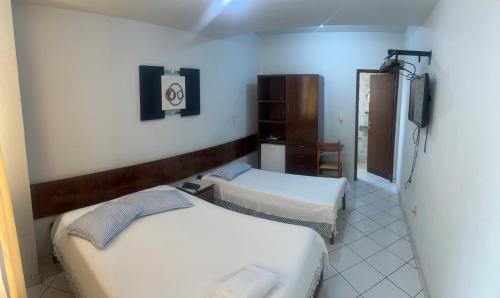 a room with two beds and a television in it at HOTEL DONA JOSA in Carmo do Cajuru