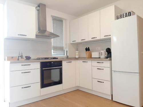 a white kitchen with white cabinets and a stove at Apartments Amavi in Izola