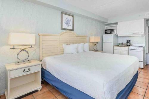 a bedroom with a large white bed and a kitchen at Oceanfront. Ground Floor. Easily Accessible. in Myrtle Beach
