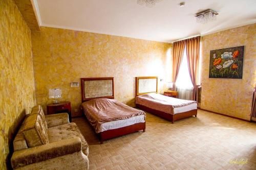 een hotelkamer met 2 bedden en een bank bij гостиница Аркалык in Arqalyq