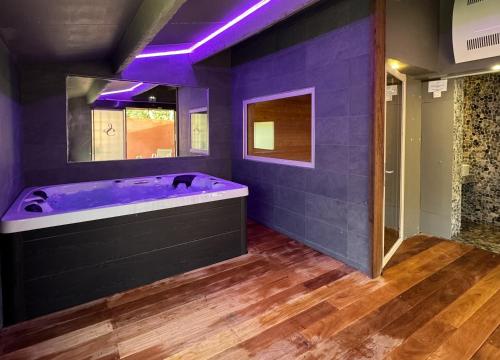 uma casa de banho roxa com uma grande banheira com iluminação roxa em Les Jardins de Cassis em Cassis