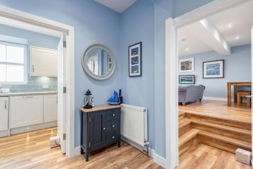 a kitchen and living room with blue walls and wooden floors at Golf Course View Apartment - Craighead - Crail in Crail