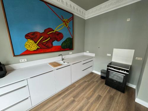 uma cozinha com armários brancos e uma pintura na parede em Art Apartments em Hamburgo