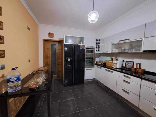 uma cozinha com um frigorífico preto e armários brancos em Sea View House em Ribeira Brava