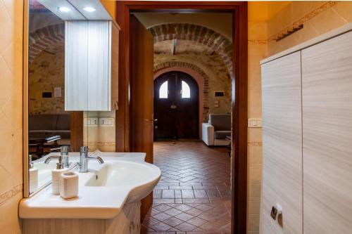 baño con lavabo, espejo y pasillo en Le Gerlette - La Stalla en Braccagni