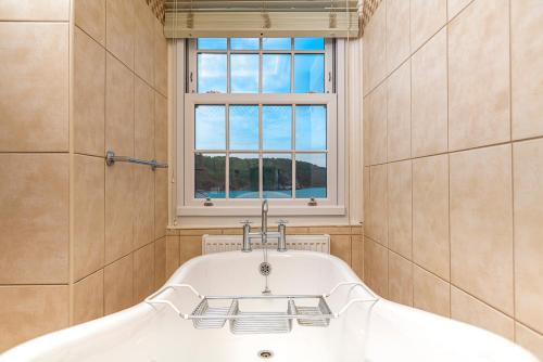 a bath tub in a bathroom with a window at Cary Arms & Spa in Torquay