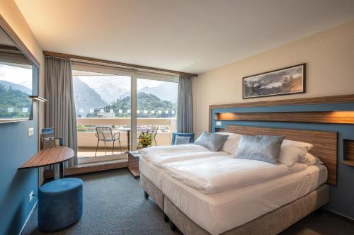 ein Hotelzimmer mit einem Bett und einem großen Fenster in der Unterkunft Metropole Swiss Quality Hotel in Interlaken