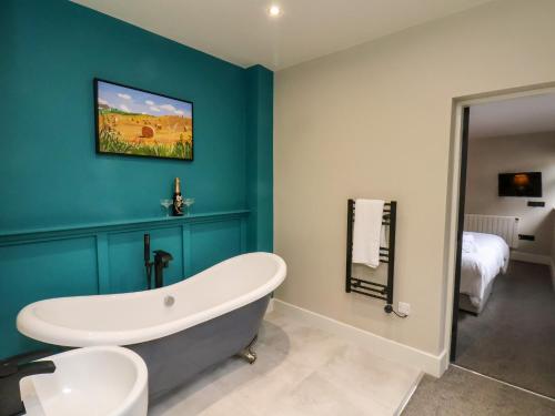 a bathroom with a white tub and a blue wall at Apt 3 Hunter's Quay in Bridlington