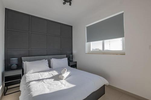 um quarto com uma grande cama branca e uma janela em BlissNest em Marsaskala