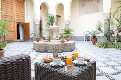 a patio with a table with food and orange juice at Riad Al Ansari in Fez