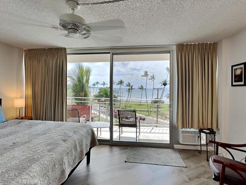 a bedroom with a bed and a view of a patio at Island Surf 506 in Kihei