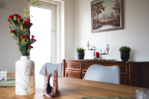 a dining room table with a vase of flowers on it at Setrið Guesthouse in Borgarnes