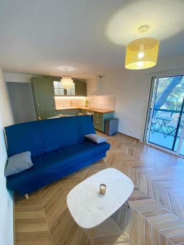 - un salon avec un canapé bleu et une table blanche dans l'établissement T2 avec clim et terrasse vue mer, les Sablettes, à La Seyne-sur-Mer