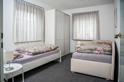 um quarto com 2 camas, uma mesa e 2 janelas em Haus Helga em Idar-Oberstein