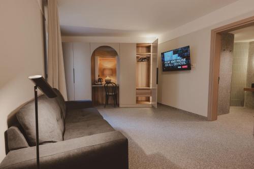 uma sala de estar com um sofá e uma televisão na parede em Maria Rosa Suites em Victoria