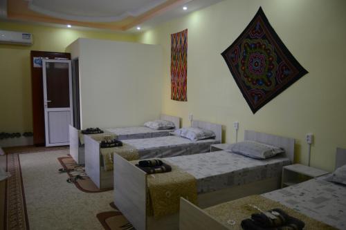 Cette chambre dispose de 4 lits et d'un mur avec une photo. dans l'établissement Orzu Guest House, à Boukhara