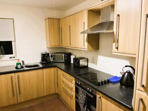 cocina con armarios de madera y encimera negra en Entire flat in Banchory, Aberdeenshire, Scotland, en Banchory