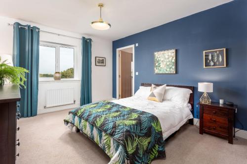 a blue bedroom with a bed and a window at 52 Hannah Wynd in Ayr