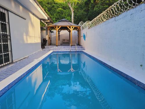 una piscina con cenador junto a un edificio en Casa Bonita en Puerto Cortés