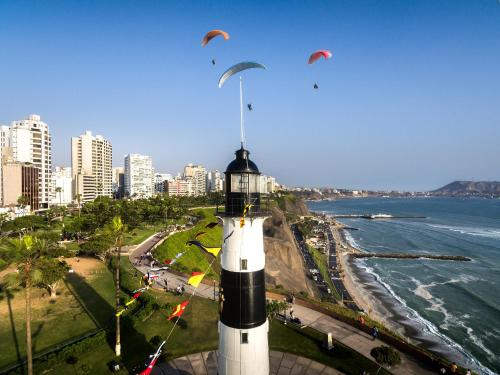 a lighthouse on the beach with kites flying above it at Kennedy Park 601 Apartment in Lima