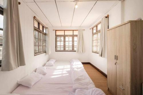 Habitación con 3 camas y ventanas. en บ้านพักเหมาหลังเชียงคาน ฮักเลย ฮักกัญ โฮมสเตย์ 1 - ຊຽງຄານ ຮັກເລີຍ ຮັກກັນ ໂຮມສະເຕ1 -Chiang Khan Hugloei HugKan Homestay1 en Chiang Khan