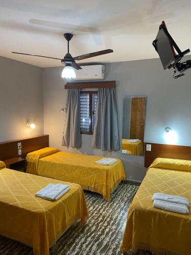 ein Hotelzimmer mit 3 Betten und einem Deckenventilator in der Unterkunft Hotel Nuevo Trento in La Banda