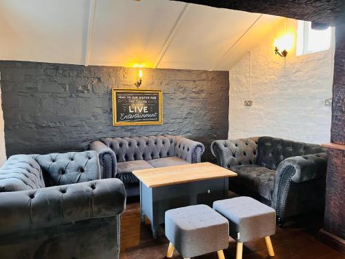 a bar with leather couches and a table and chairs at The Unicorn Hotel in Somerton